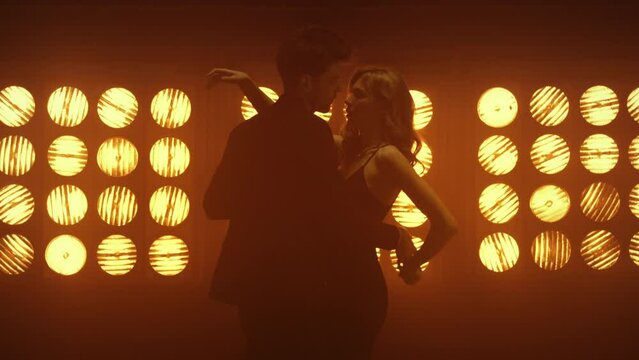 Man twirling sexy woman in sensual dance. Hot guy bending girl dancing in club.