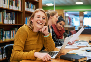 She is certain that she will pass the test. Portrait of a cheerful young female student working on...