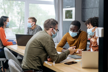 employees in protective masks work in the hall of the coworking center.
