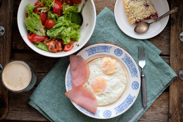 Breakfast. Salad with tomatoes and lettuce, scrambled eggs with bacon and a piece of crumble