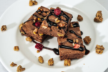Chocolate brownie squares with walnut pieces, chocolate threads and granola. Natural, healthy food concept.
