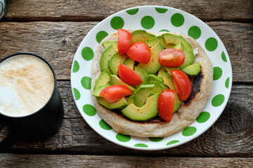 Flatbread with avocado and tomato. Wooden background, top view