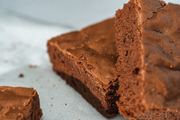 Close up of cubes of chocolate brownies on a white plate on a marble table.