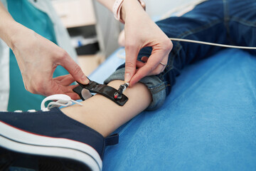 Doctor hands putting electrocardiograph sensor on child leg - Powered by Adobe