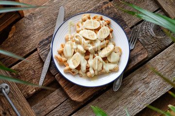Waffles with banana and white chocolate. Wooden background. Top view. 