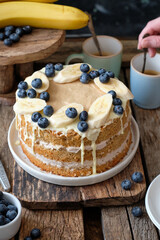 Banana cake with blueberries and white chocolate. Wooden background, side view