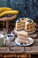 Banana cake with blueberries and white chocolate. Wooden background, side view
