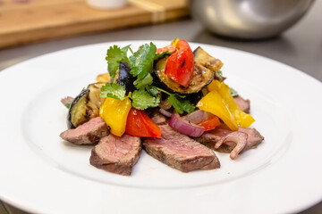 A salad of baked eggplant, sweet pepper and beef with parsley is on a plate