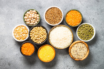 Gluten free cereals. Different bowls with rice, buckwheat, corn, lentils, soy beans and quinoa at stone table. Allergen free food. Top view.