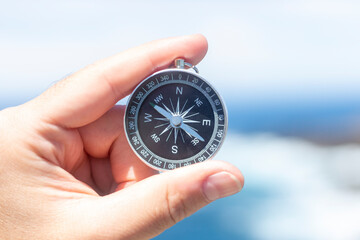 Closeup, hand holding an analog compass in front of the sea, summer concept, holidays, travelling....