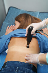 Woman receiving extracorporeal shockwave therapy in clinic