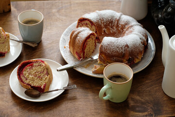 Raspberry roll wreath. Brioche. Side view, wooden background, coffee, powdered sugar, yeast buns. 