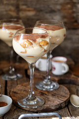 Portioned tiramisu in a glass. Wooden background, side view