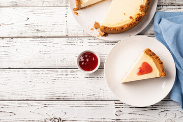 Tasty homemade cheesecake on white wooden table with strawberry jam