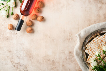 Passover celebration concept. Matzah, red kosher walnut and spring beautiful rose flowers.. Traditional ritual Jewish bread on sand color old concrete background. Passover food. Pesach Jewish holiday.