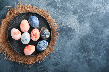 Easter eggs. Dyed Easter eggs with marble stone effect ref and blue color in rustic style on dark  stone background. Easter background. Top view.