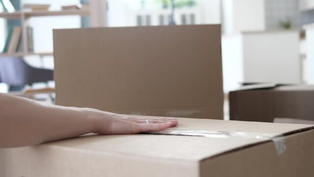 Closing a box with things with adhesive tape, moving to a new apartment, house, country. Population migration concept