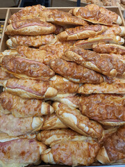 Freshly baked white Czech rohlik bread with bacon and melted cheese on top, called English rohlik in bakery or grocery store. Grilled bread roll. Close-up of display in supermarket