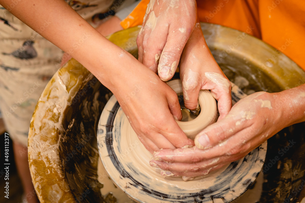 Wall mural potter working on potters wheel with clay. process of making ceramic tableware in pottery workshop. 