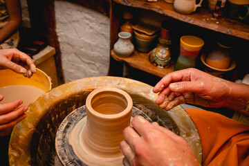 Potter working on potters wheel with clay. Process of making ceramic tableware in pottery workshop. Handicraft and art concept.