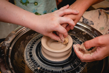 Fototapeta premium Potter working on potters wheel with clay. Process of making ceramic tableware in pottery workshop. Handicraft and art concept.