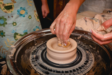 Potter working on potters wheel with clay. Process of making ceramic tableware in pottery workshop. Handicraft and art concept.