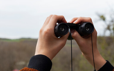 man looking through binoculars while hiking