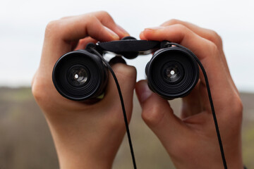 man looking through binoculars while hiking
