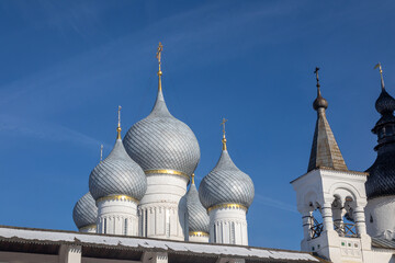 Fototapeta na wymiar Beautiful church with domes against the blue sky. Winter sunny day. Colorful light. Ancient architecture. Cross on domes.