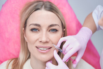Beauty salon client getting subcutaneous injection into smile line