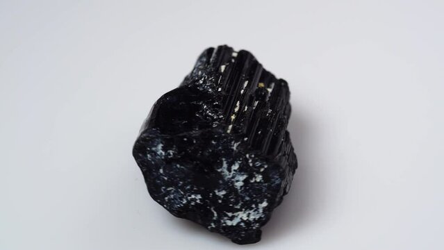 black tourmaline scherl rough specimen on the white background turning table