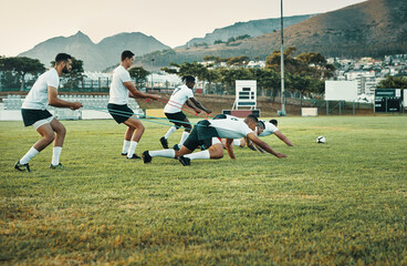 Let nothing stop you from reaching your goal. Full length shot of a group of young rugby players training with bands on the field during the day.