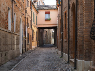 Ferrara, Italy. Downtown, medieval cobbled street with archway.