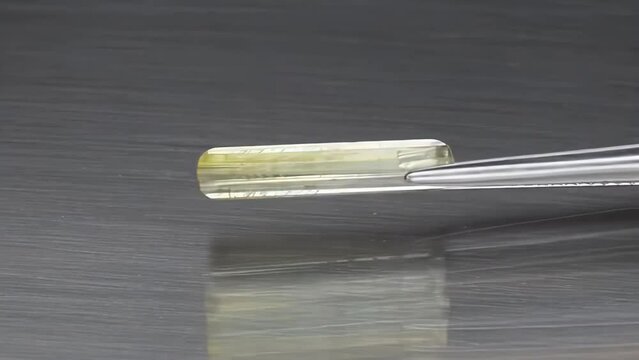 natural bi-color polychromatic tourmaline baguette cut in the tweezers
