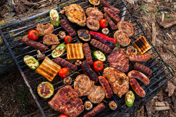 A large variety of grilled meat on the fire outside. Picnic with meat: sausages, pork steak, chicken breast with vegetables. 