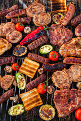 A large variety of grilled meat on the fire outside. Picnic with meat: sausages, pork steak, chicken breast with vegetables. 