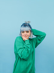Cute hipster girl with colored hair isolated on blue background, looking at camera and posing. Vertical