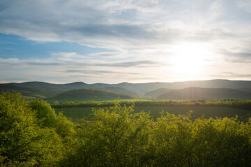 Beautiful green mountain landscape with sun and sun rays over the hills.