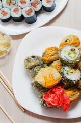 Fried rolls lie on a plate with red ginger leaves. Close-up, selective focus. Vertical photography.