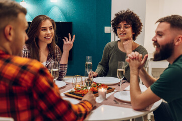 Group of friends enjoying dinner while sitting at the kitchen table together
