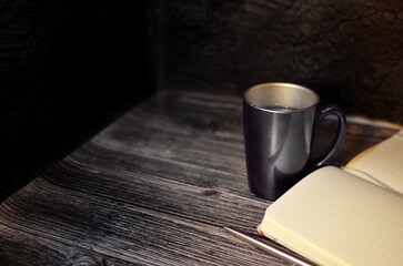 A cup of coffee and notebook on the wooden table