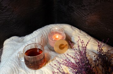 Cup of tea and pink candle on the white wool
