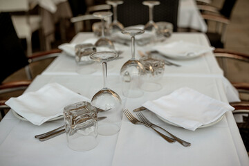 Beautiful table setting. Empty glasses, cutlery and napkin on a plates, table with a white tablecloth in an Italian restaurant.