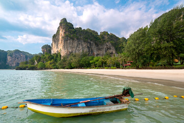 Empty exotic beach, high cliffs and fishing boat in the foreground. Railay Beach, Ao Nang, Krabi, Thailand