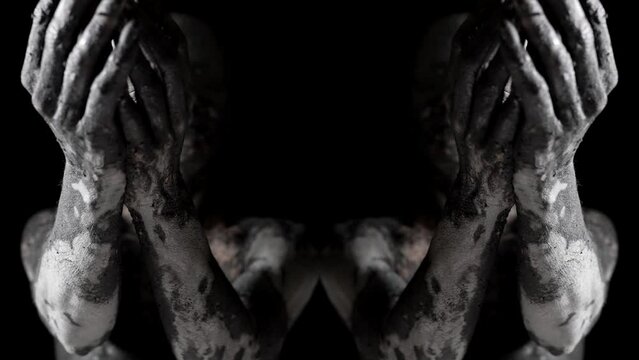 strange woman covered by dirt or clay is stretching hands to camera from darkness, double image
