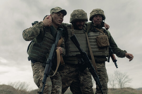 Two Ukrainian soldiers drag wounded warrior after battle against russian enemy.