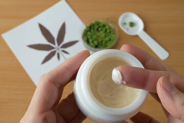 Cannabis cream cosmetic in dose with marijuana plant for hand on wooden background. Cannabis cosmetics