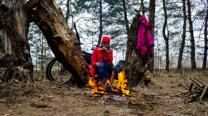 girl by the fire in camping clothes for the off-season. bike trips. gravel bike. hiking