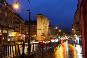 Porte Saint-Denis at rainy night . It is a Parisian monument located in the 10th arrondissement of Paris, France.