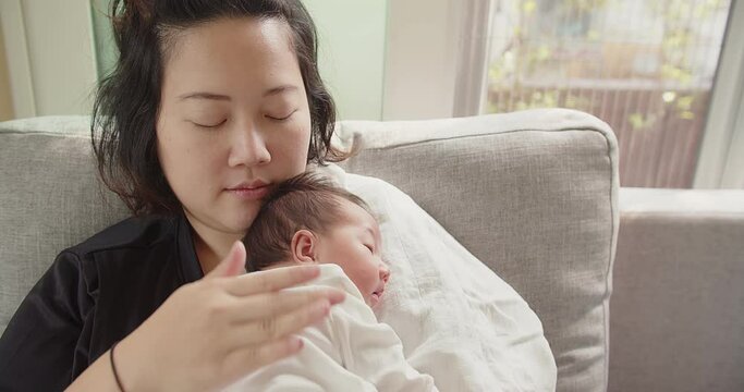 Happy family Asian mother holding caressing hugging newborn baby infant, mom hand being burped and patted rubbed on the back of the child to encourage burping after eating full milk, parenthood, love